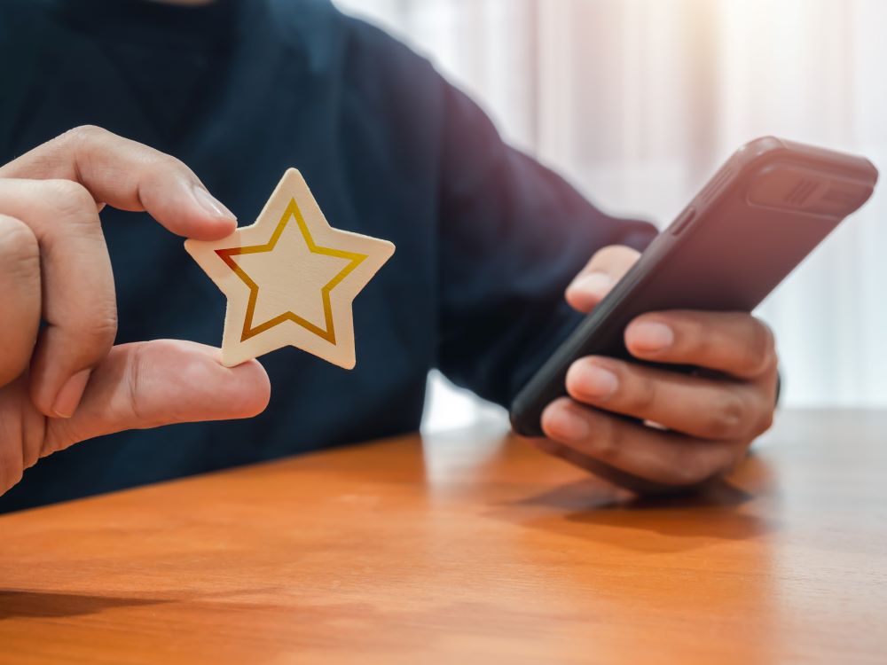 Revisão de cliente, satisfação, feedback, conceitos de pesquisa. Estrela de madeira na mão de uma pessoa que usa um smartphone para avaliar a experiência de serviço e a pesquisa de satisfação de negócios em um site ou aplicativo.