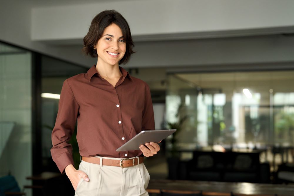 Retrato de jovem mulher profissional hispânica em pé no cargo. Feliz executiva de empresa feminina, empresária sorridente gerente líder corporativo olhando para a câmera usando tablet.